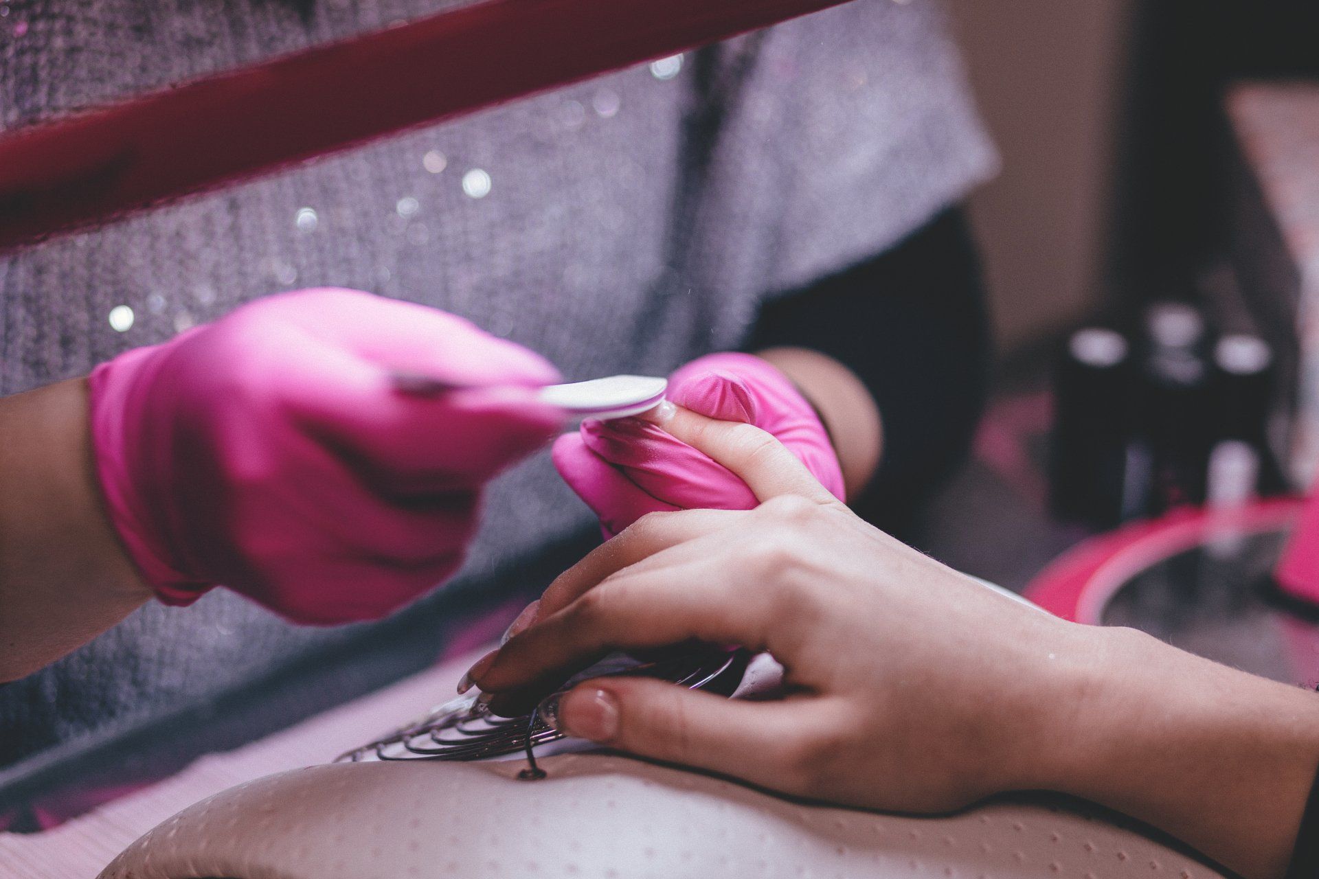 A woman is getting her nails done by a nail artist in a salon.