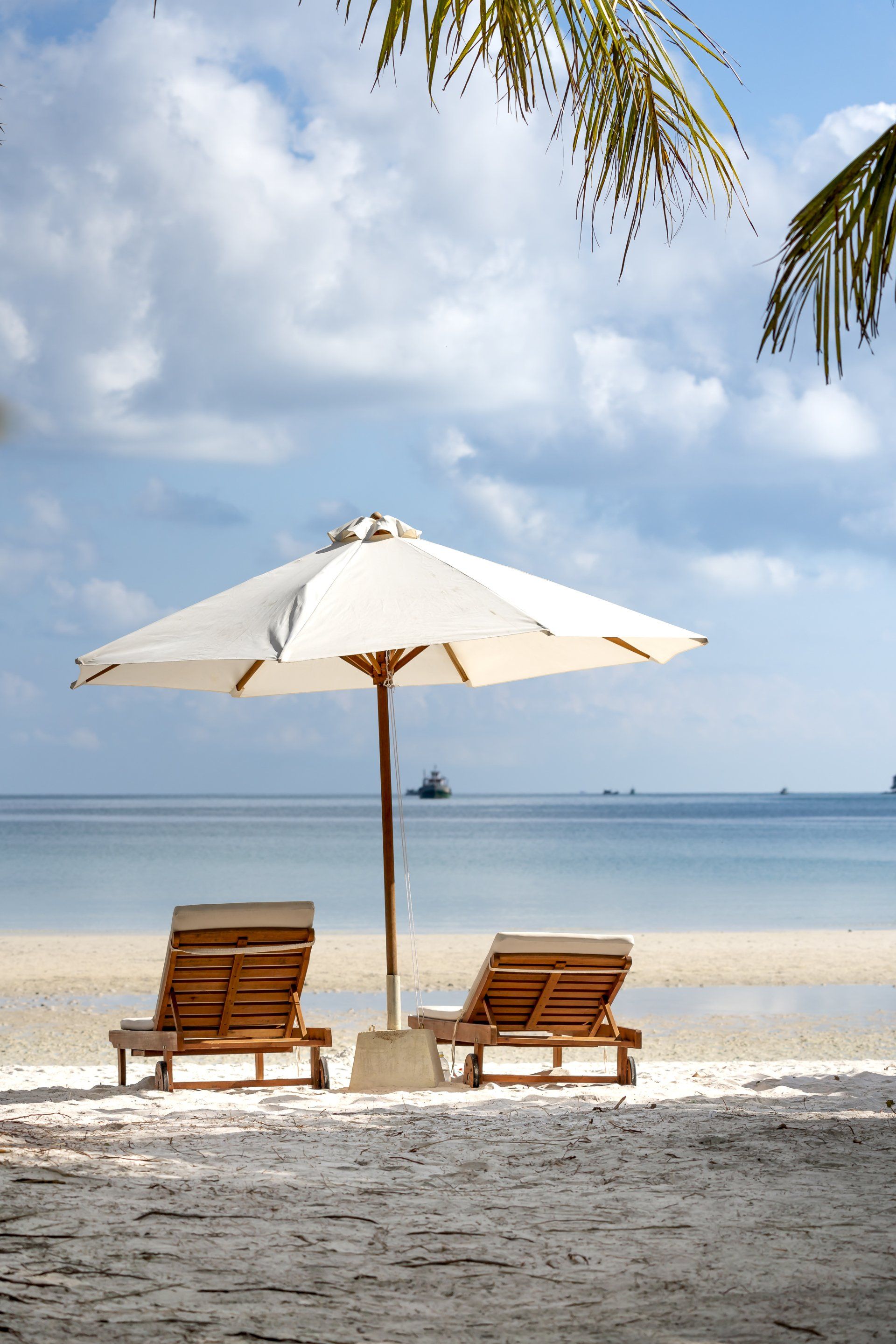 Two lounge chairs under an umbrella on a beach