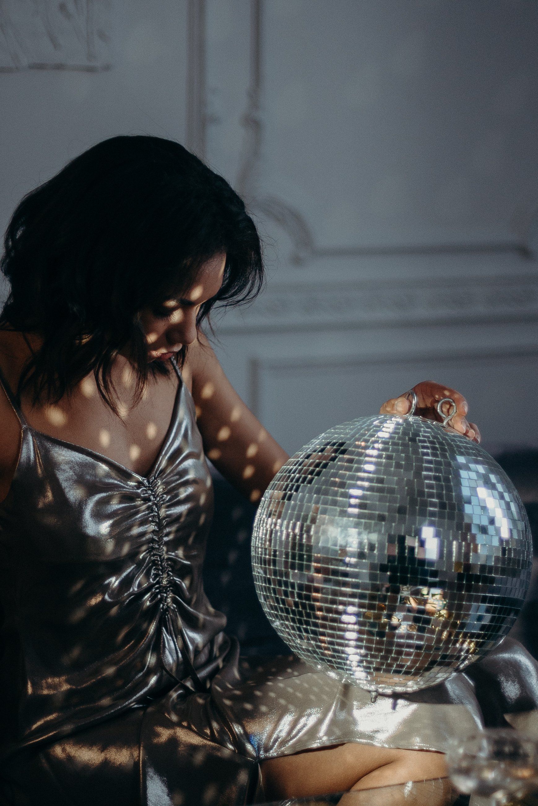 A woman is sitting on a couch holding a disco ball.
