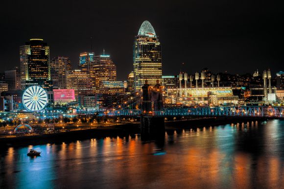 A city skyline at night with a ferris wheel in the foreground.