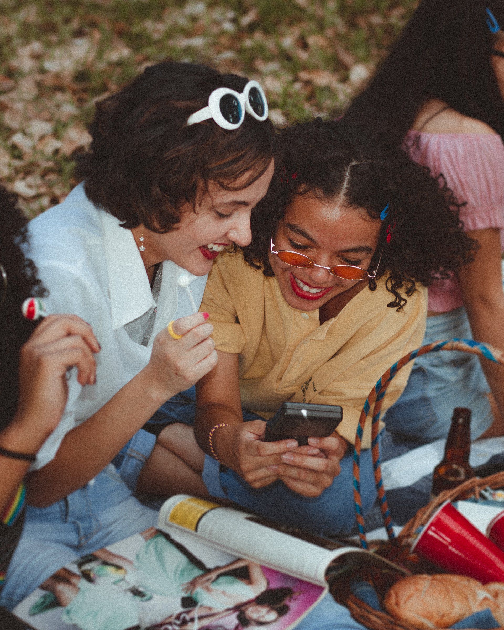 Um grupo de jovens está sentado no chão olhando para um celular.