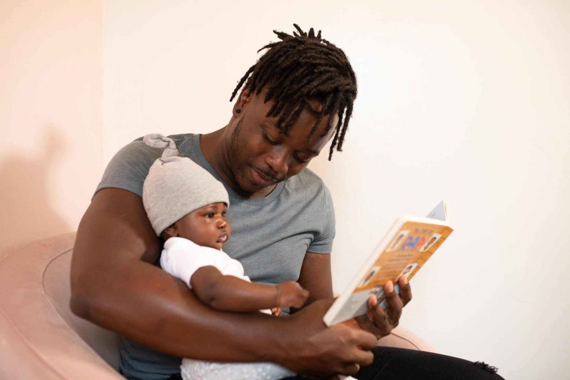 a man is holding a baby while reading a book .
