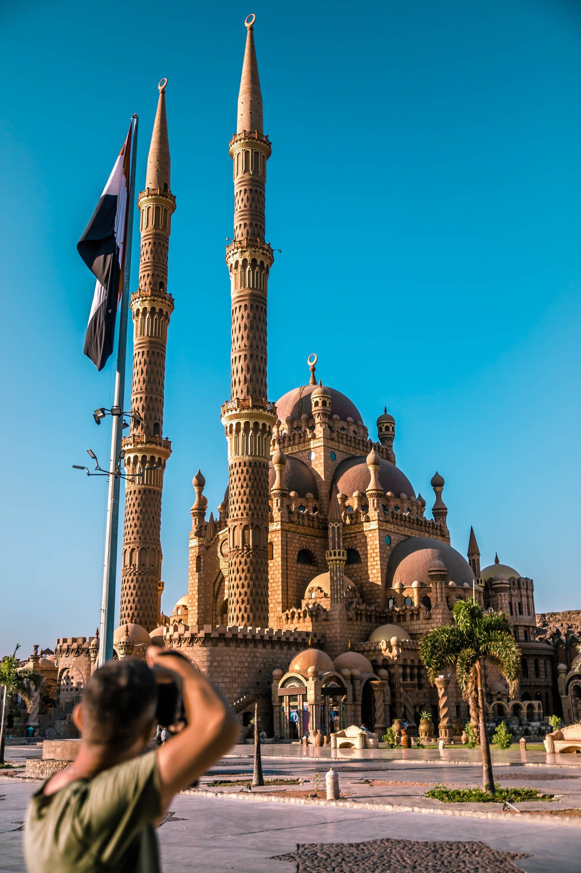 A man is taking a picture of a mosque with a camera.