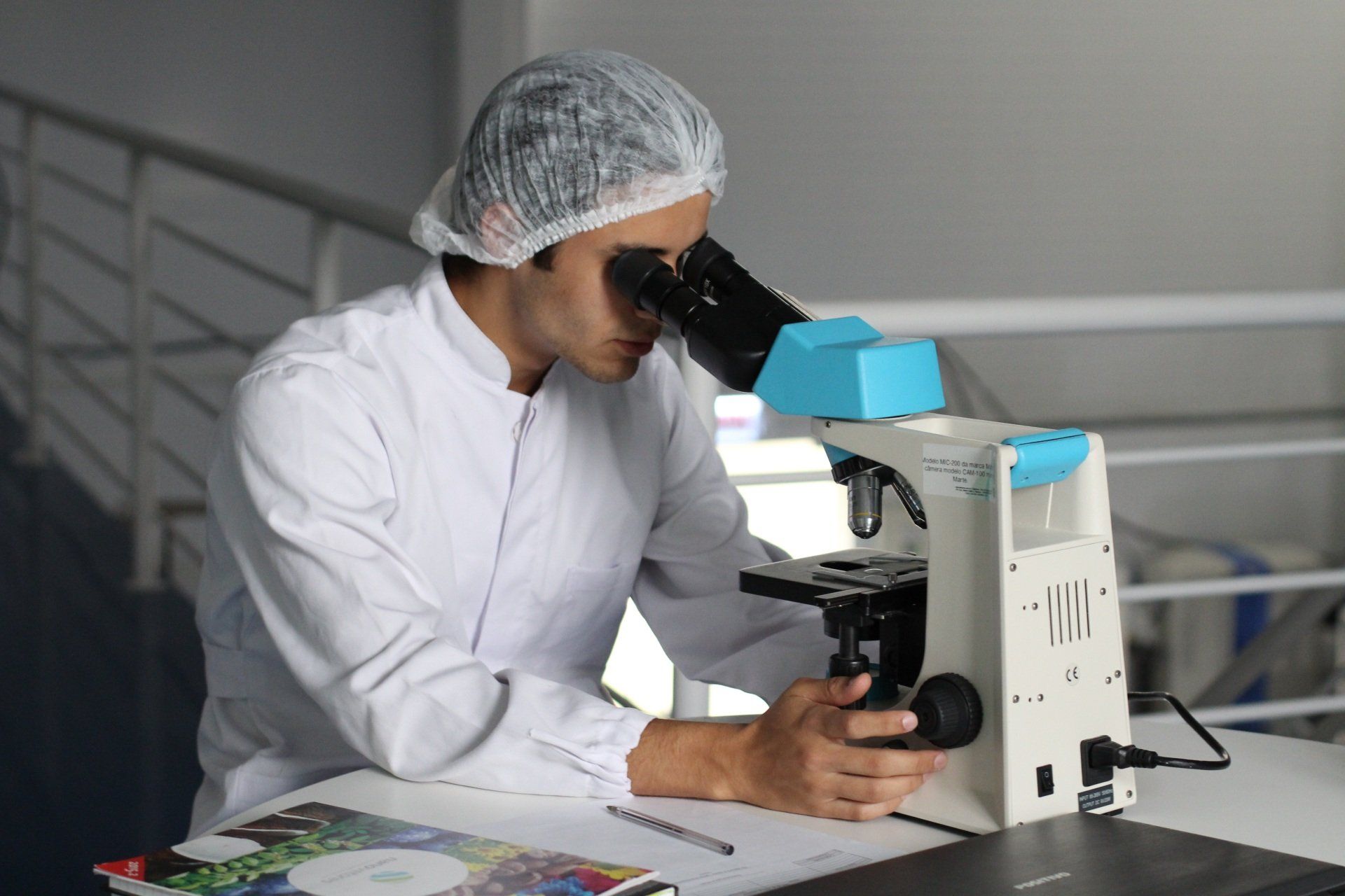 A man is looking through a microscope in a lab.