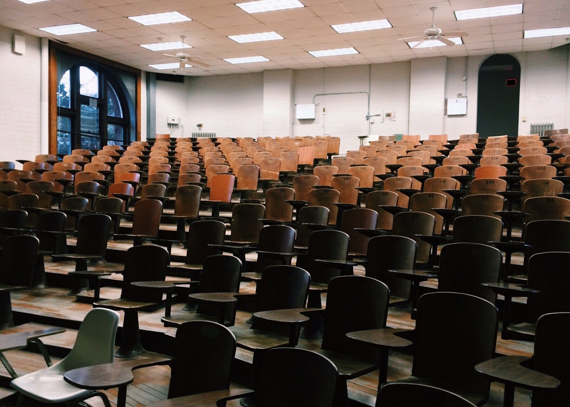 An empty lecture hall with rows of wooden chairs