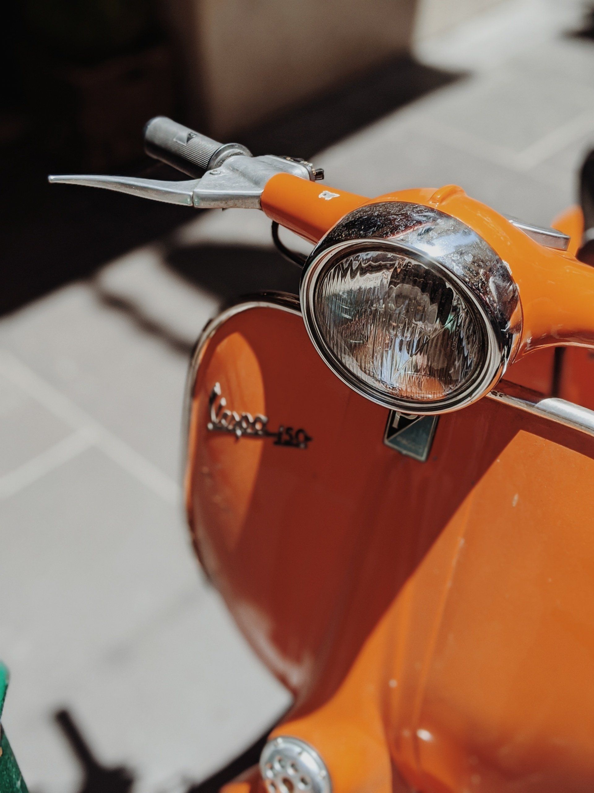 Et nærbilde av en oransje vespa-scooter på et fortau