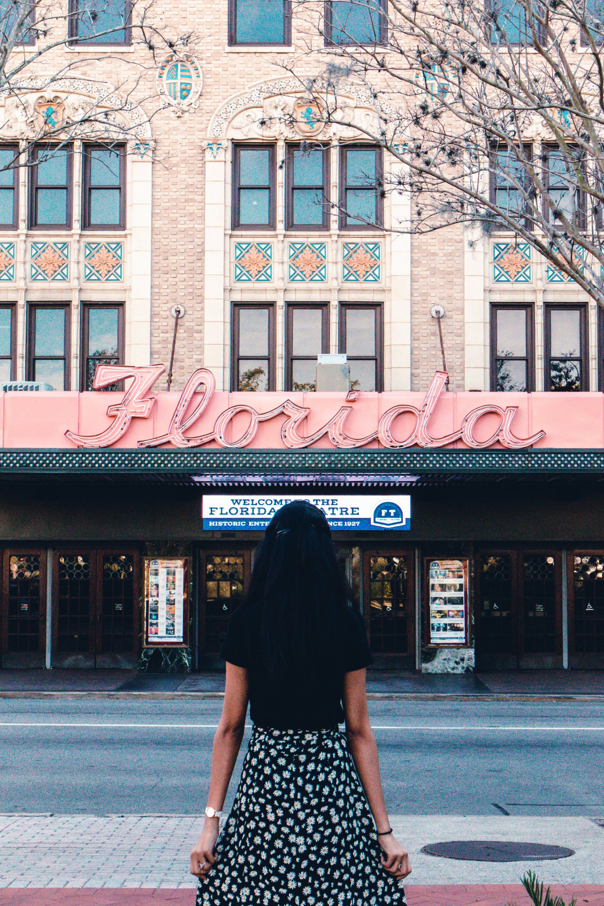 A woman is standing in front of a building with the word florida on it.