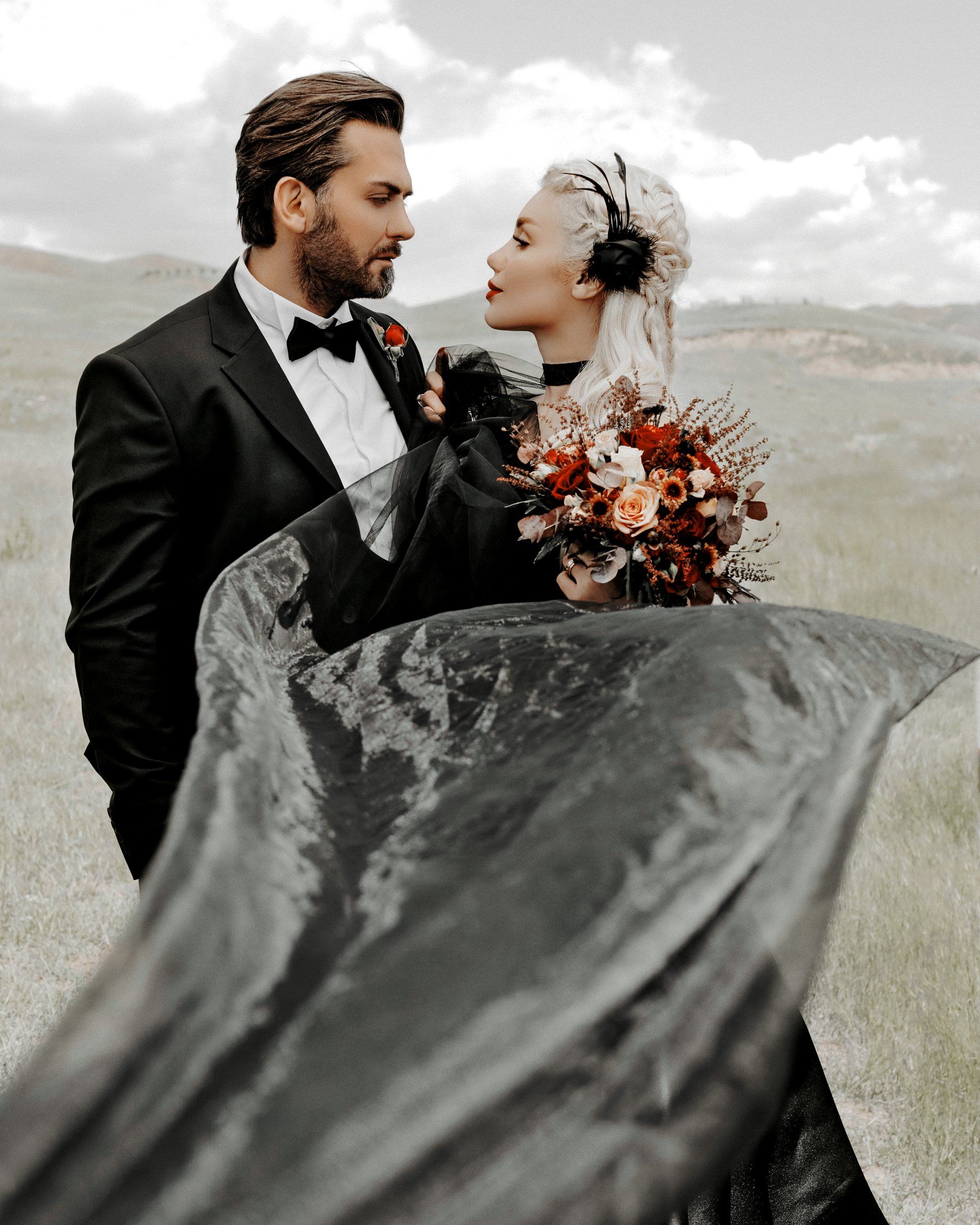 The bride is wearing a black dress and the groom is wearing a tuxedo.