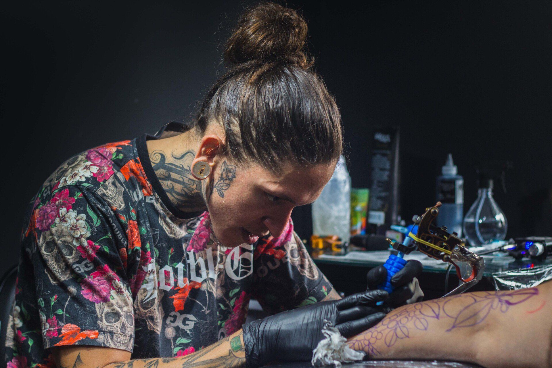 A woman is getting a tattoo on a person 's leg.