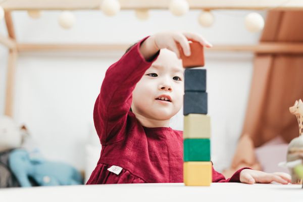 A little girl is playing with wooden blocks on a table.