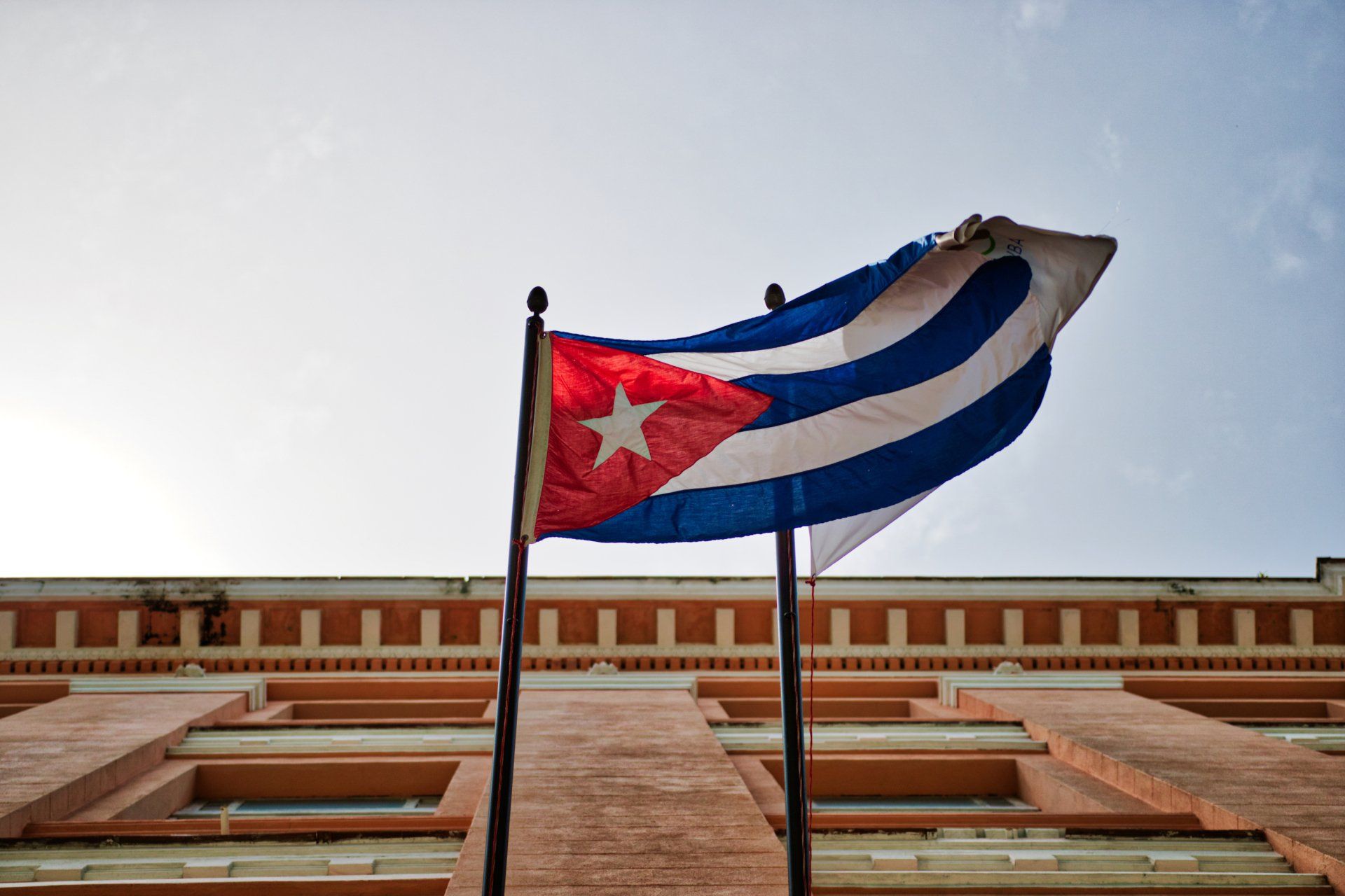 Dos banderas cubanas ondean frente a un edificio.