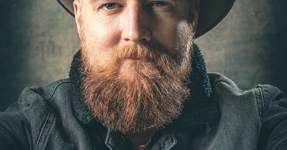 Man with a large, reddish-brown beard and hat, looking directly at the viewer.