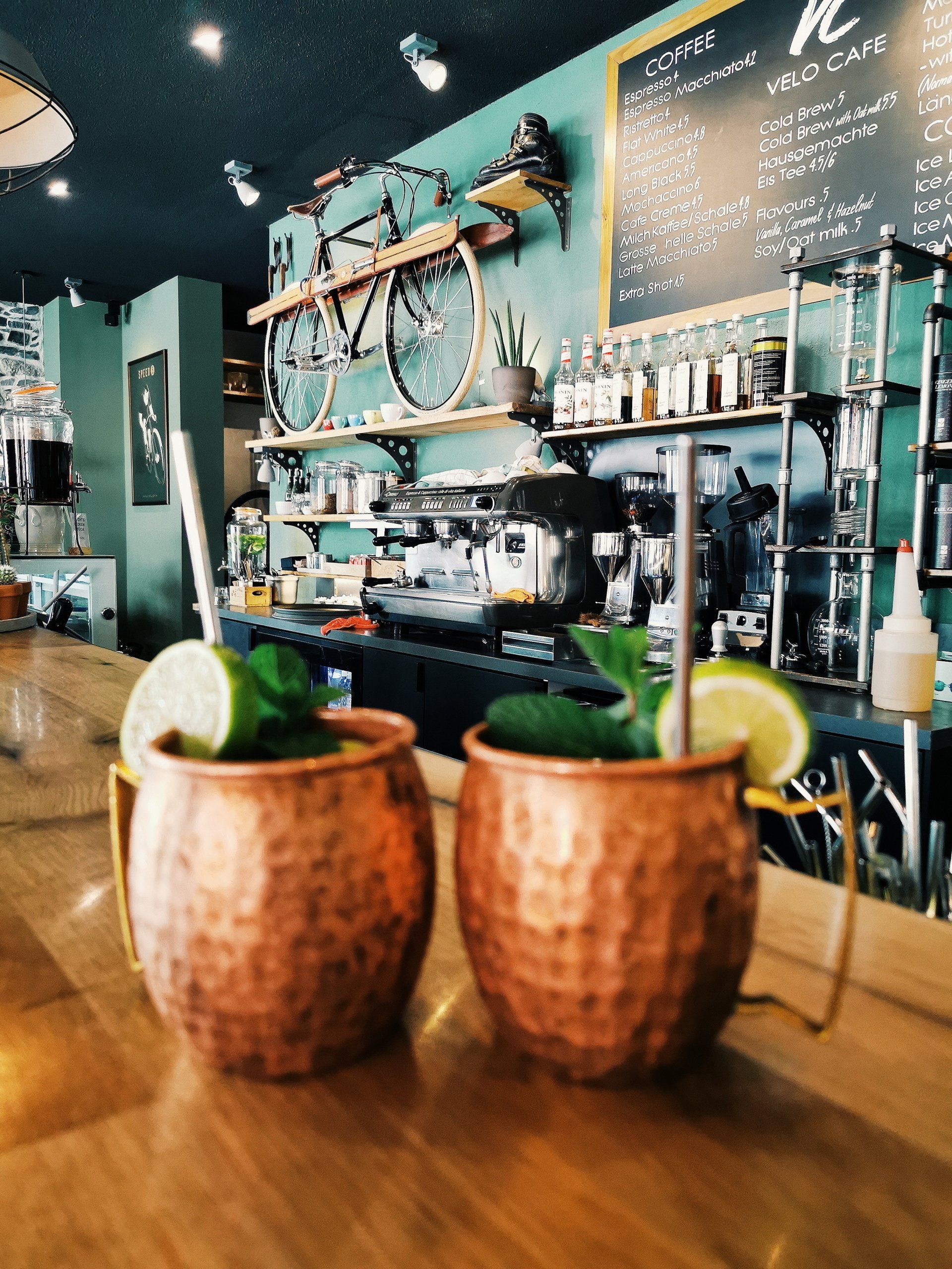Two copper mugs with lime wedges on a wooden table in a café bar