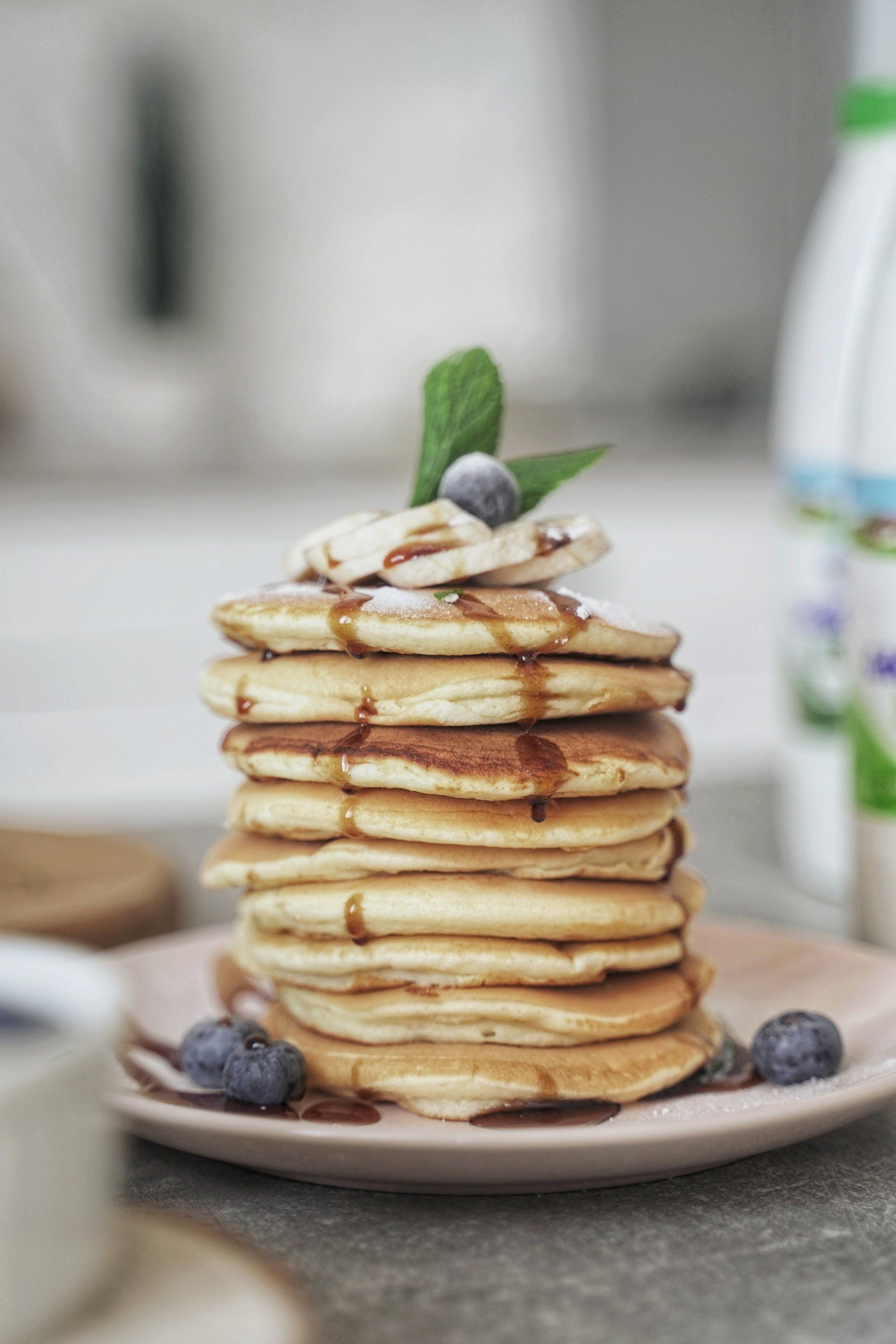 Stack of pancakes topped with berries and mint on a plate