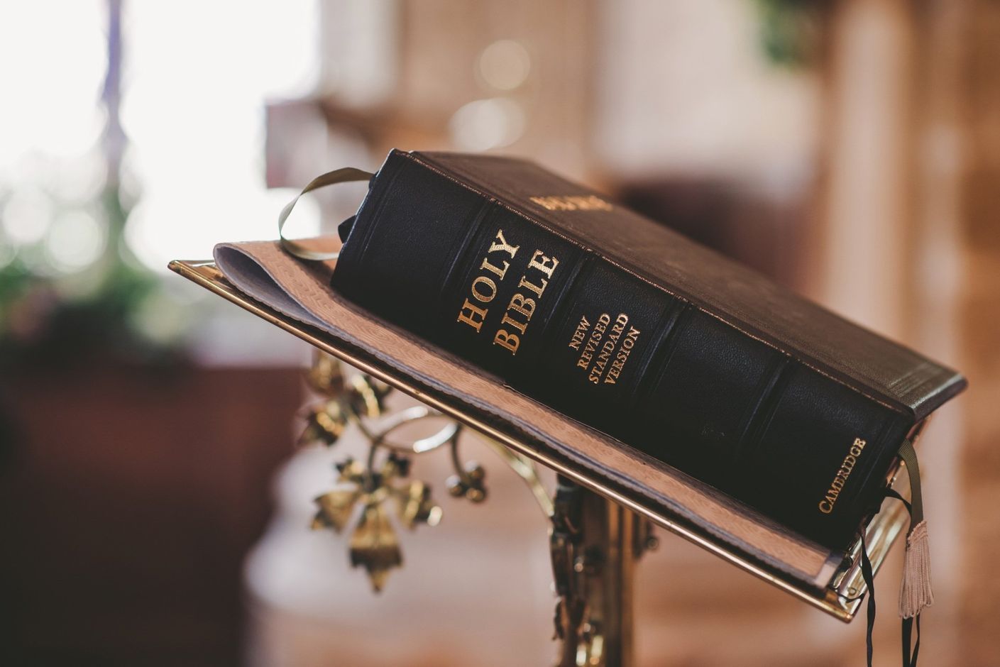A holy bible is sitting on a stand in a church.