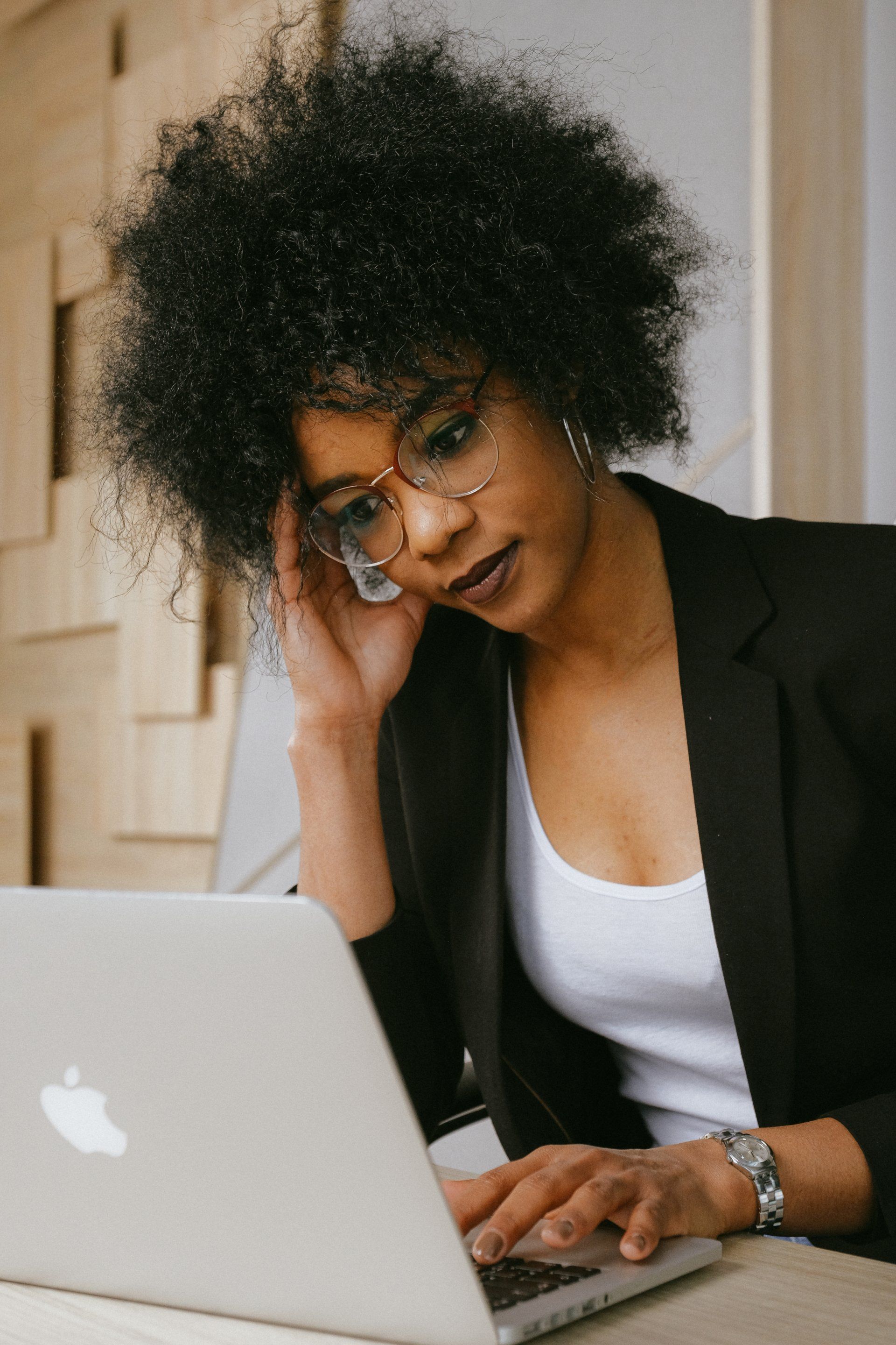 a woman wearing glasses is using an apple laptop