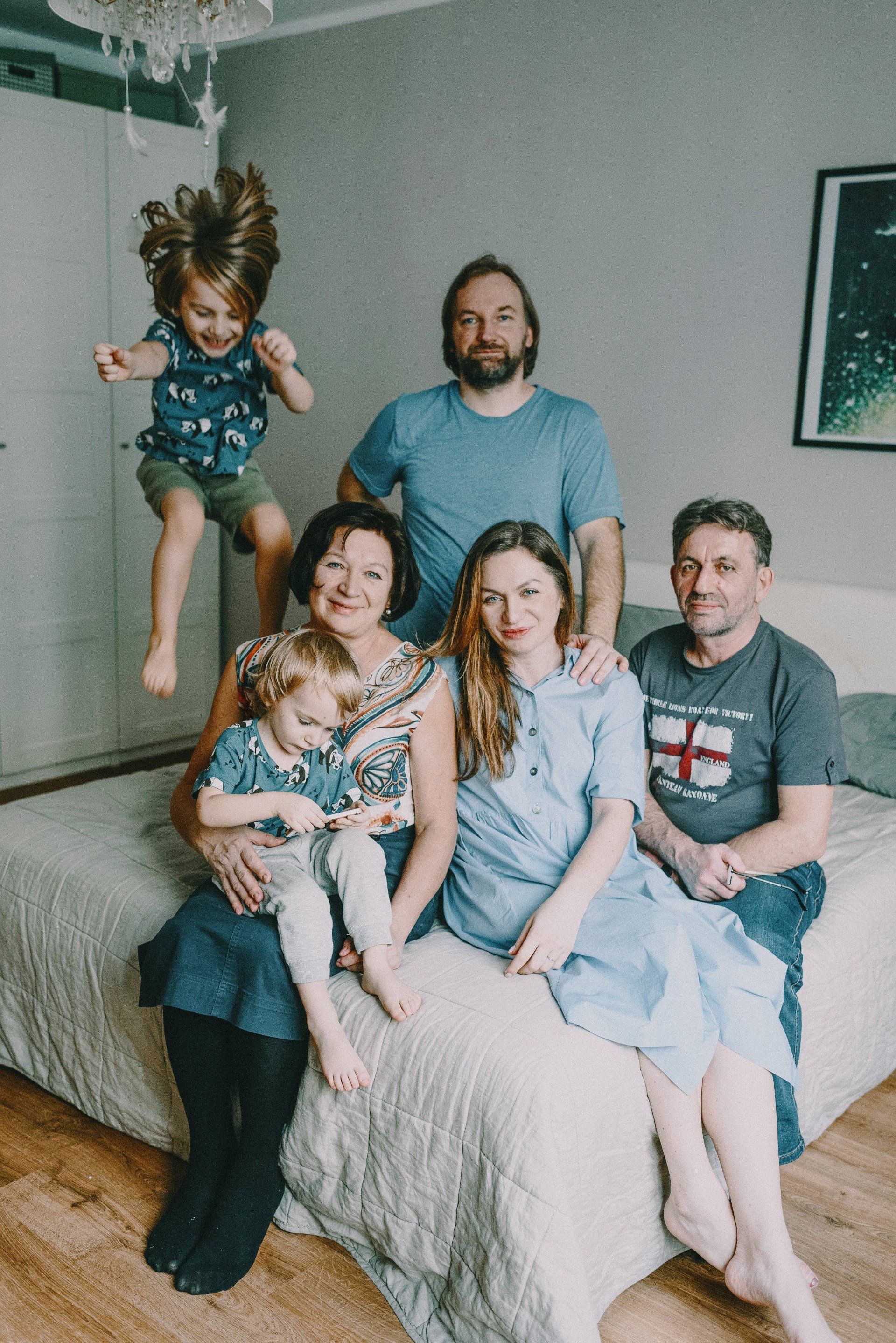 A family is posing for a picture while sitting on a bed.