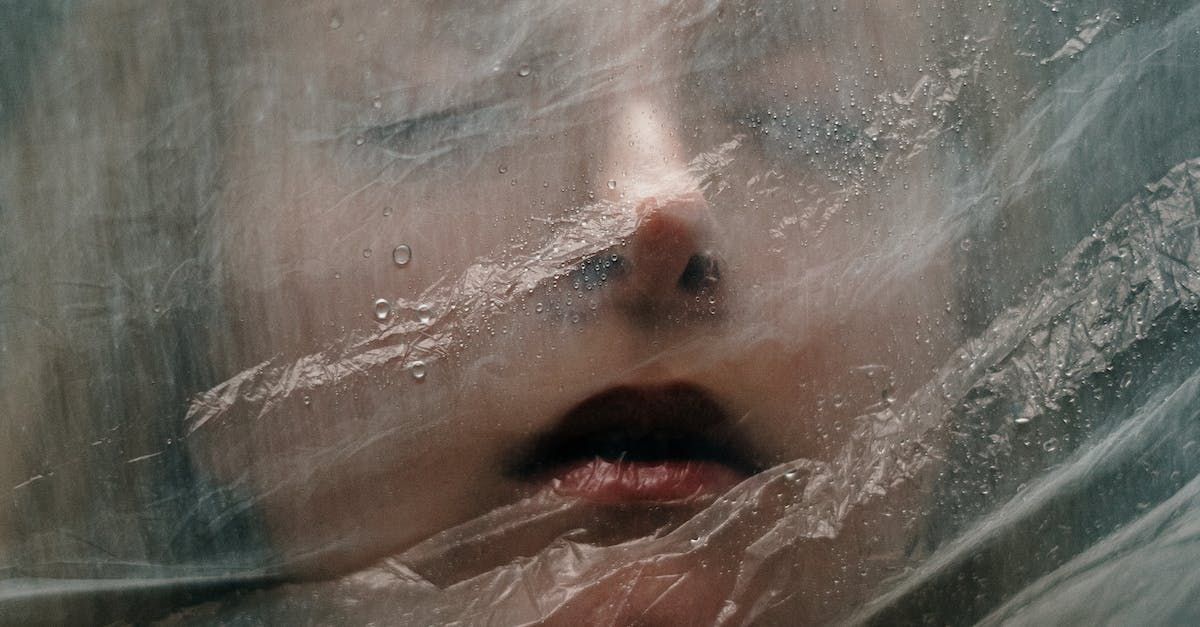 Close-up of a face pressed against and obscured by translucent plastic wrap.