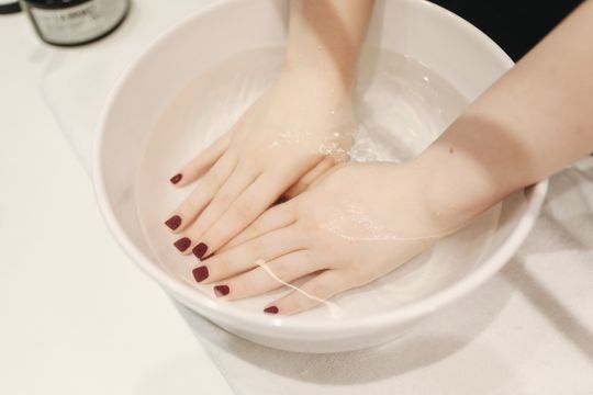 A woman is washing her hands in a bowl of water