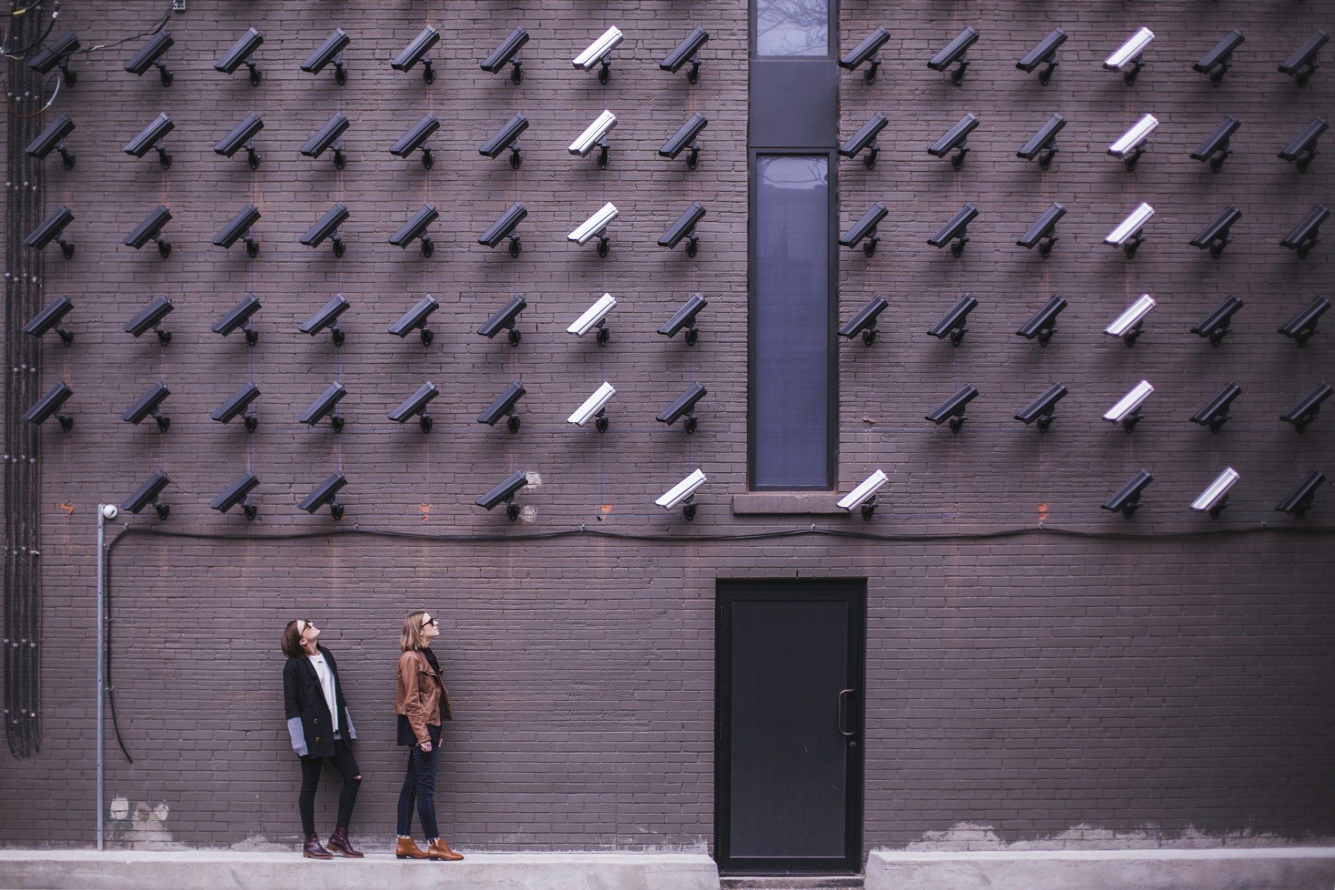 Twee vrouwen staan voor een muur met veel vogels erop.