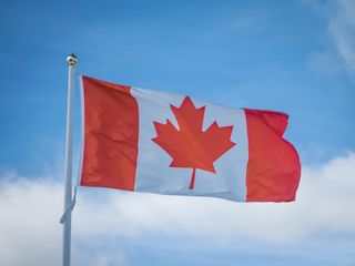 Canadian flag waving against a blue sky