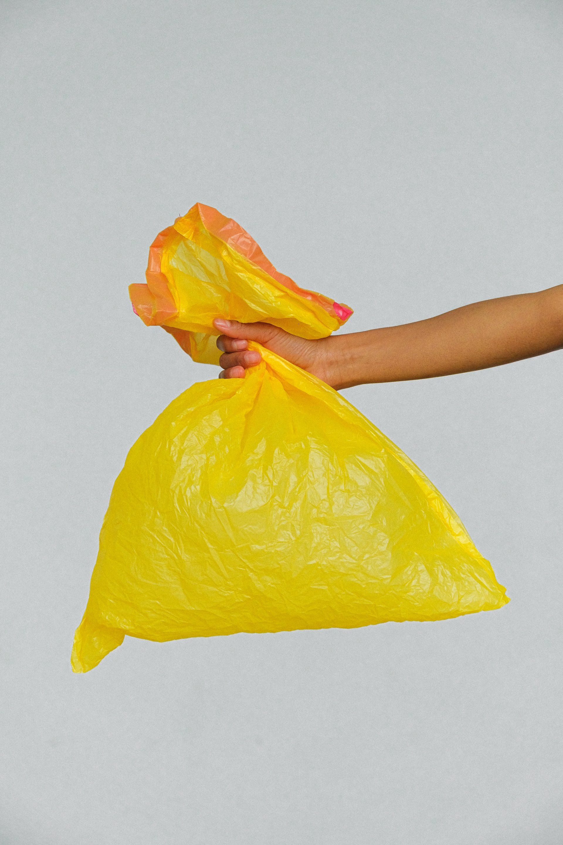 A person is holding a yellow plastic bag in their hand.