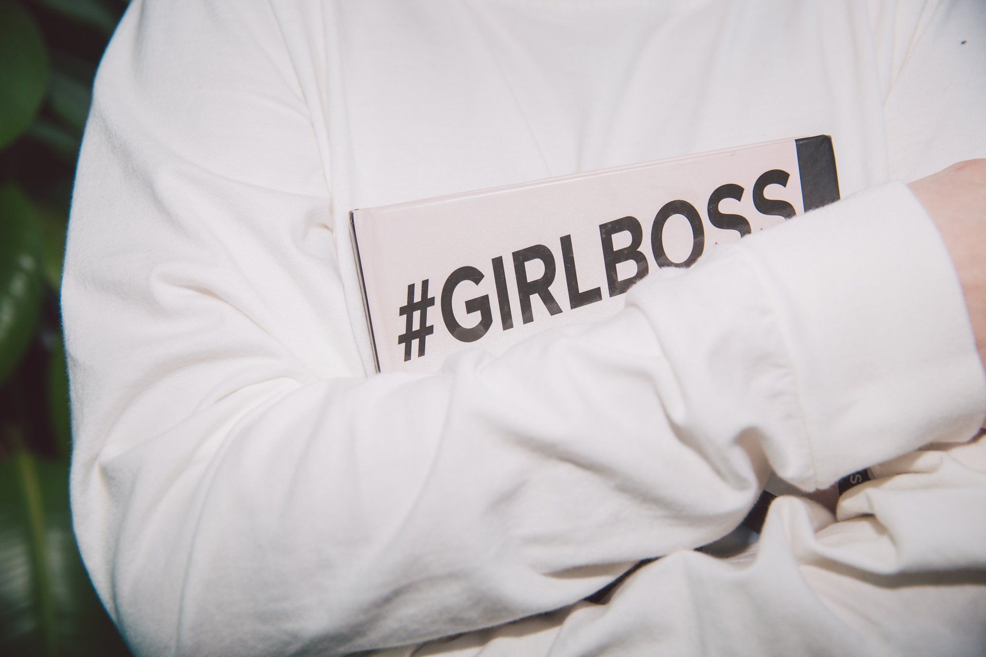 A close up of a person wearing a white sweatshirt with the word girl boss on it.