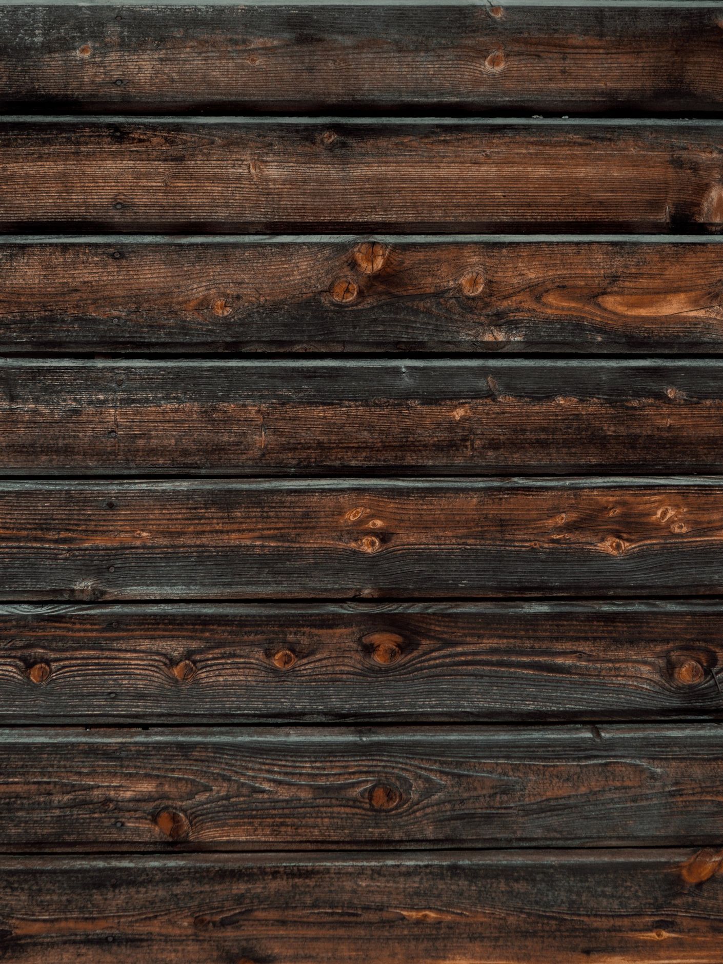Dark brown, weathered wooden planks arranged horizontally.