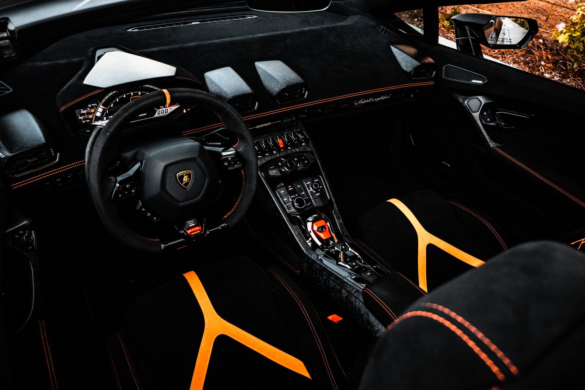 The interior of a black and orange sports car with a steering wheel.