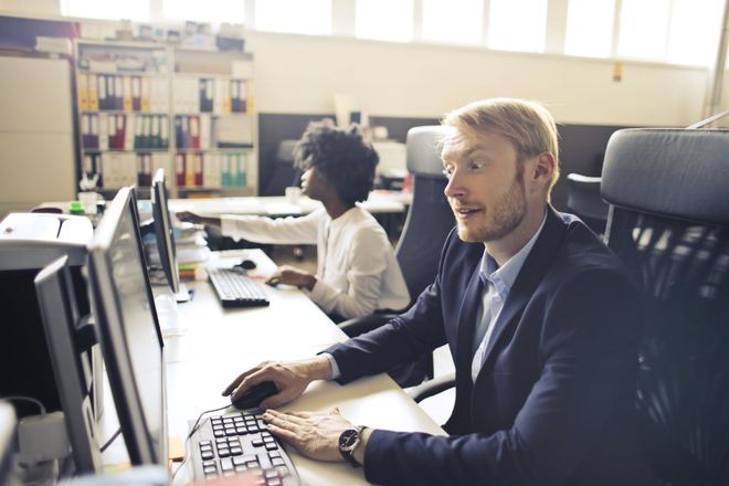 Office workers at computer desks in a bright open-plan workspace