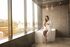 A woman in a bathrobe is sitting on a bathtub in a bathroom.