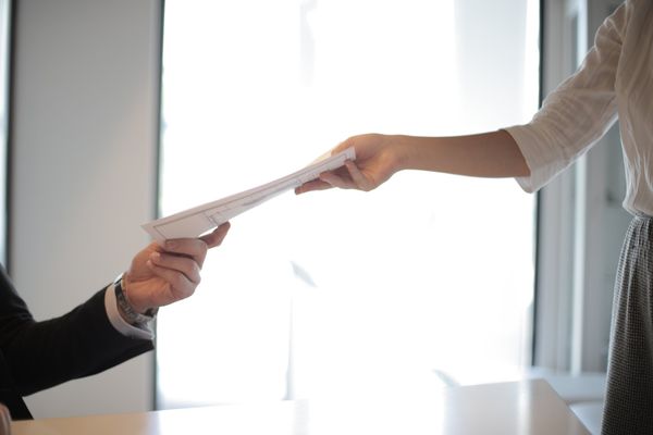 a woman is handing a piece of paper to a man .