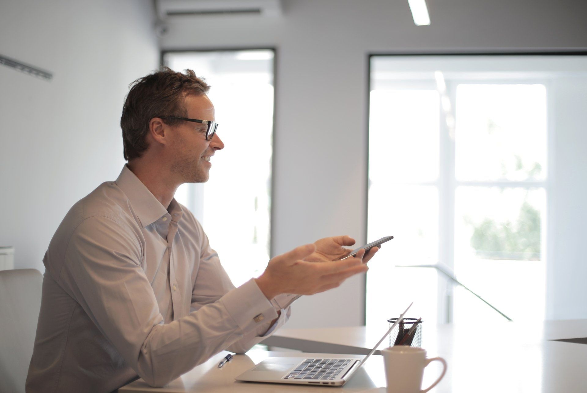 a man is sitting at a desk looking at his cell phone