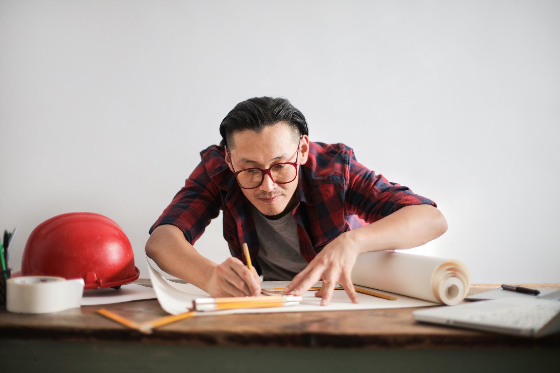 A man is sitting at a table drawing on a piece of paper.
