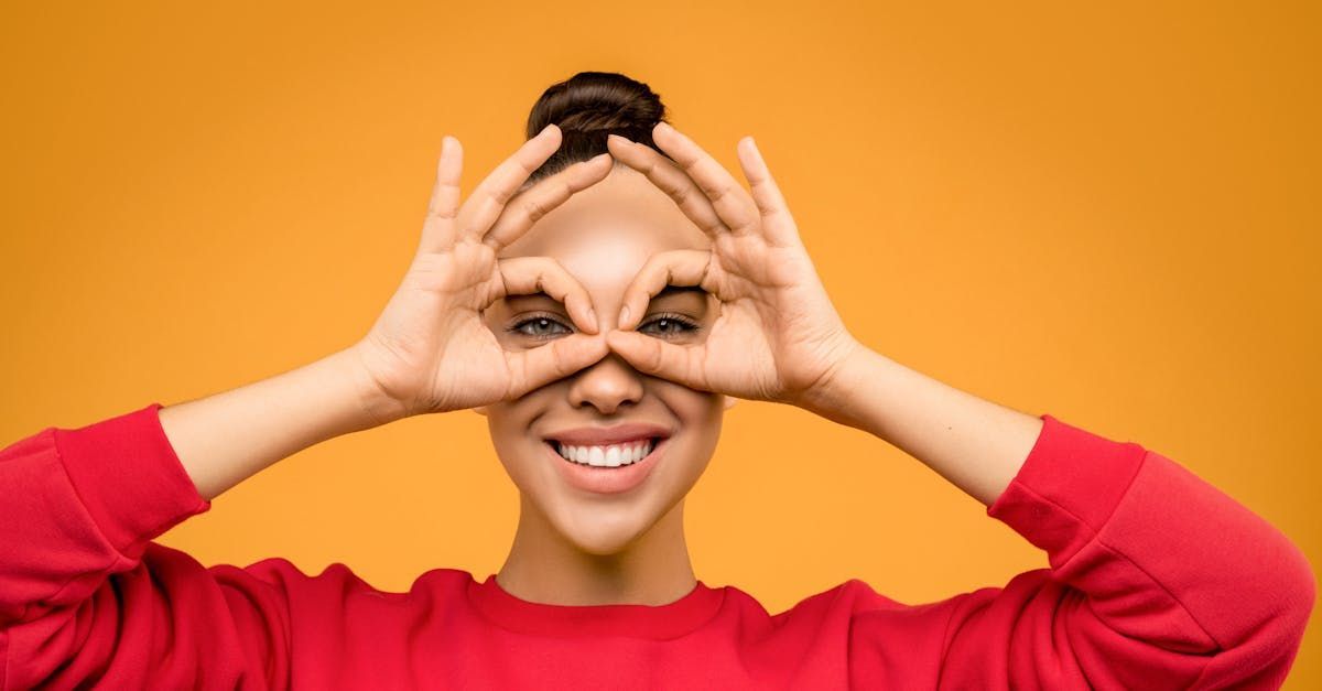 A woman in a red sweater is making a funny face with her hands.