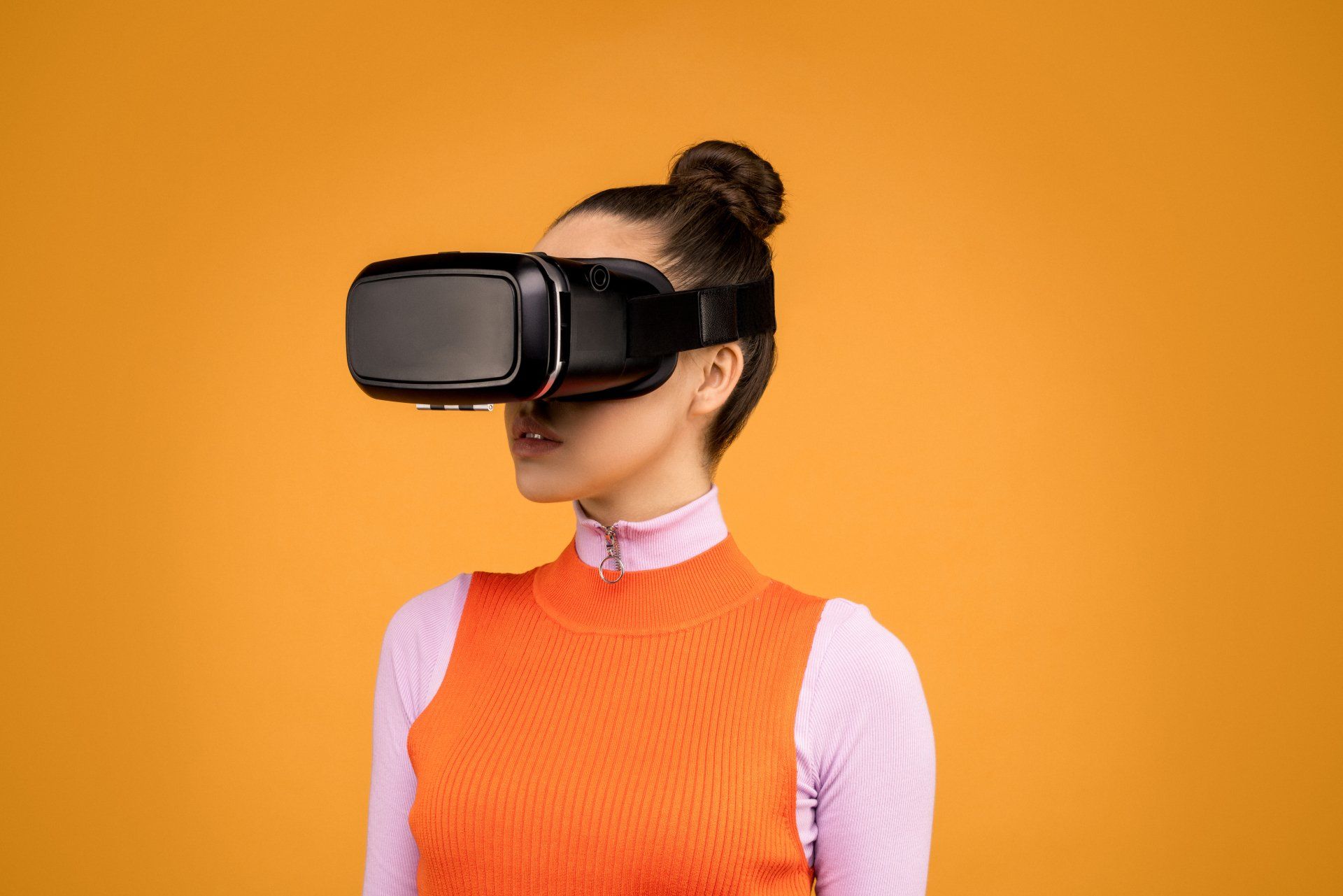 Woman wearing VR headset against orange background.
