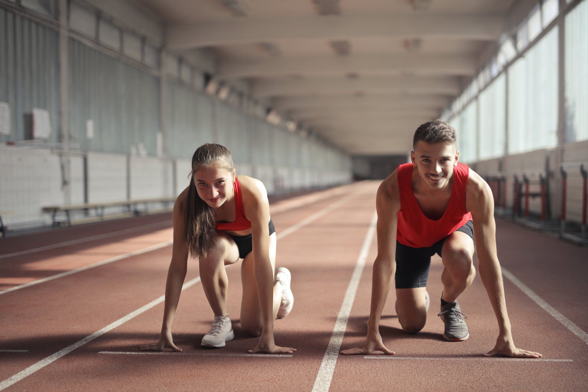 A man and a woman are getting ready to run on a track.