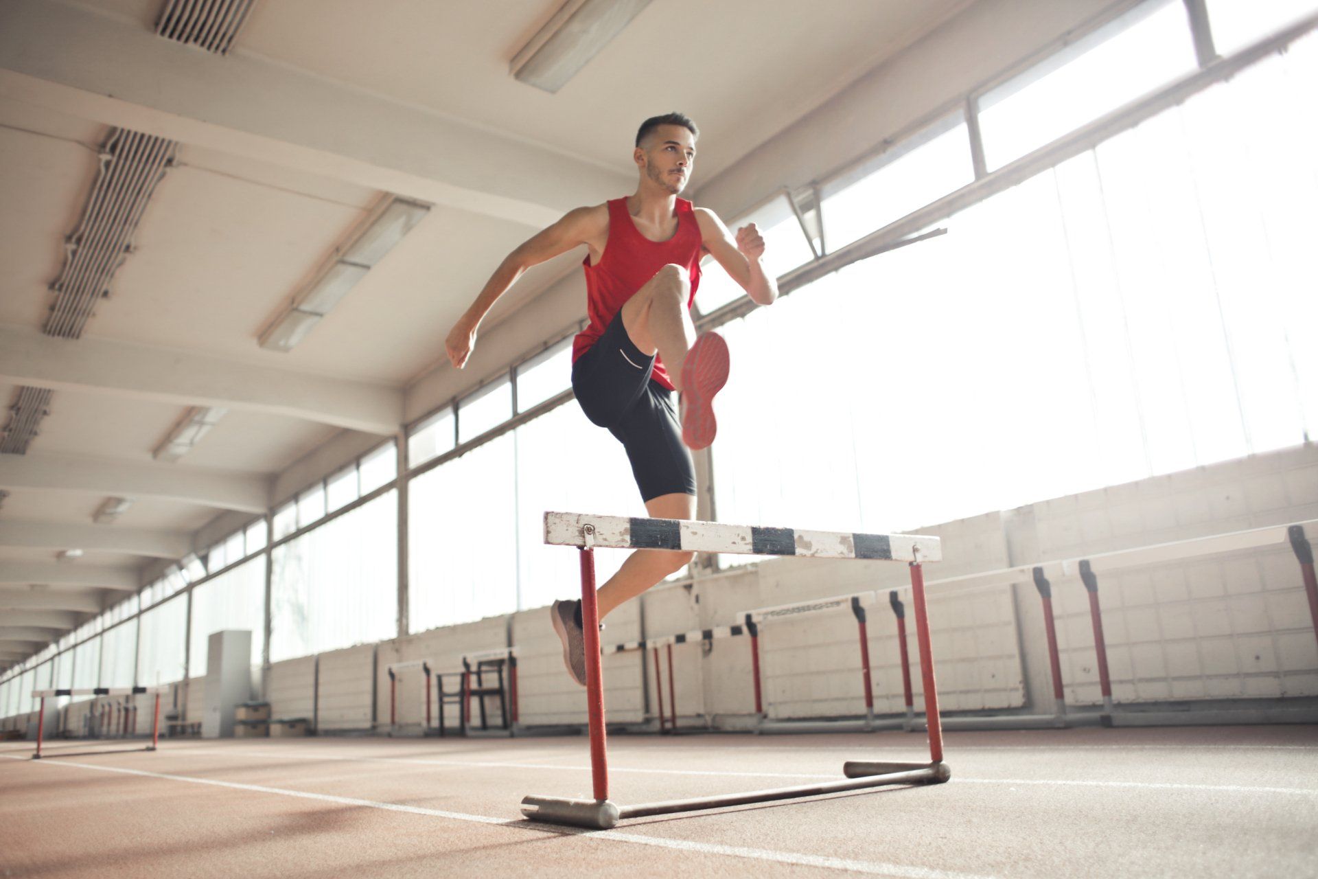 A man is jumping over a hurdle on a track.