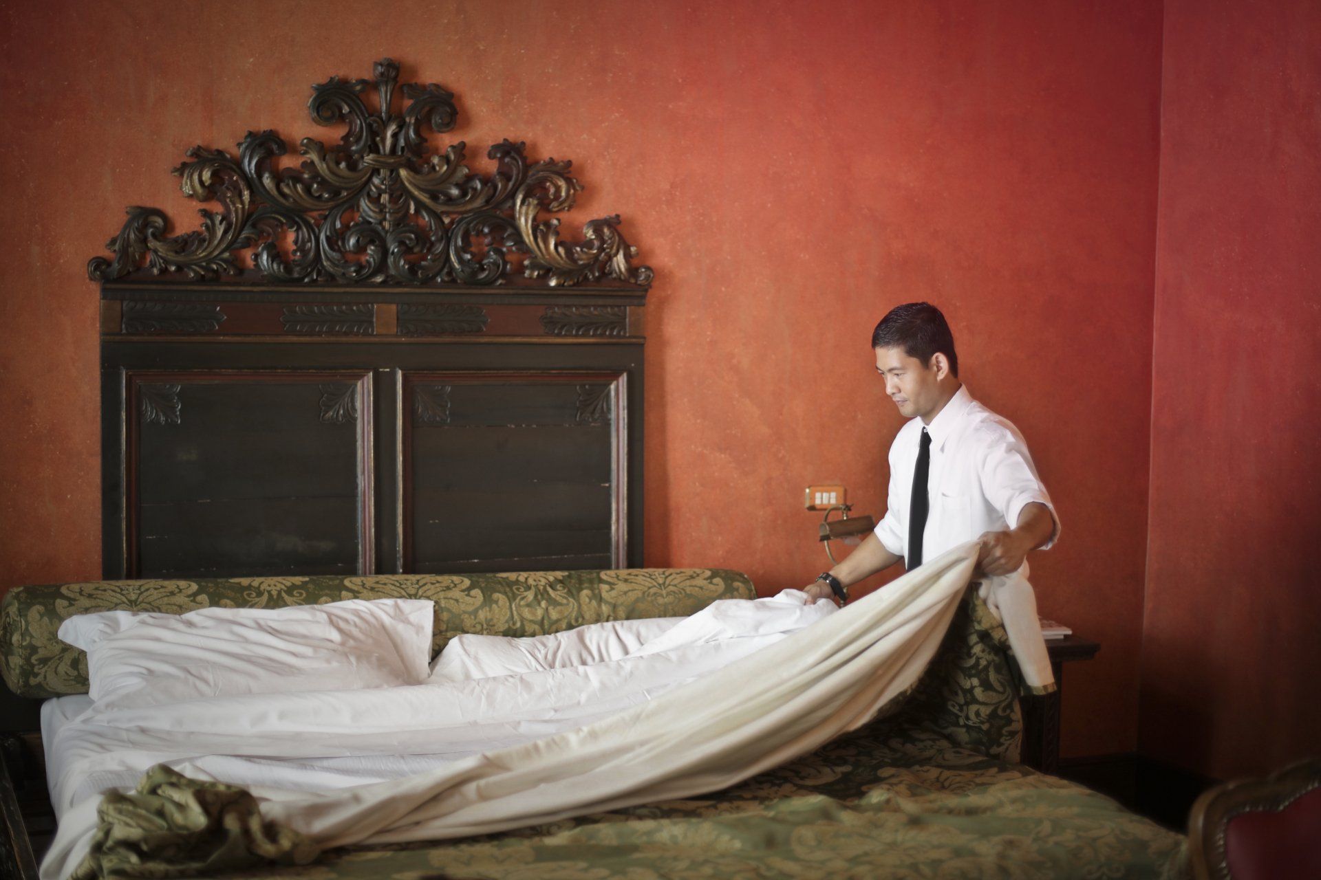 A man is making a bed in a hotel room.