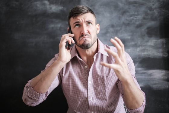 A man is making a funny face while talking on a cell phone.