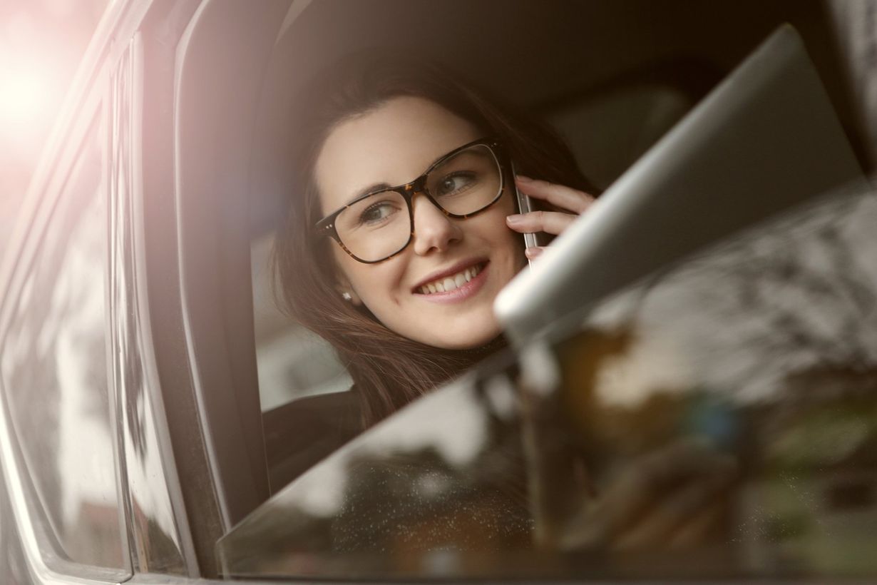 a woman wearing glasses is smiling while talking on a cell phone