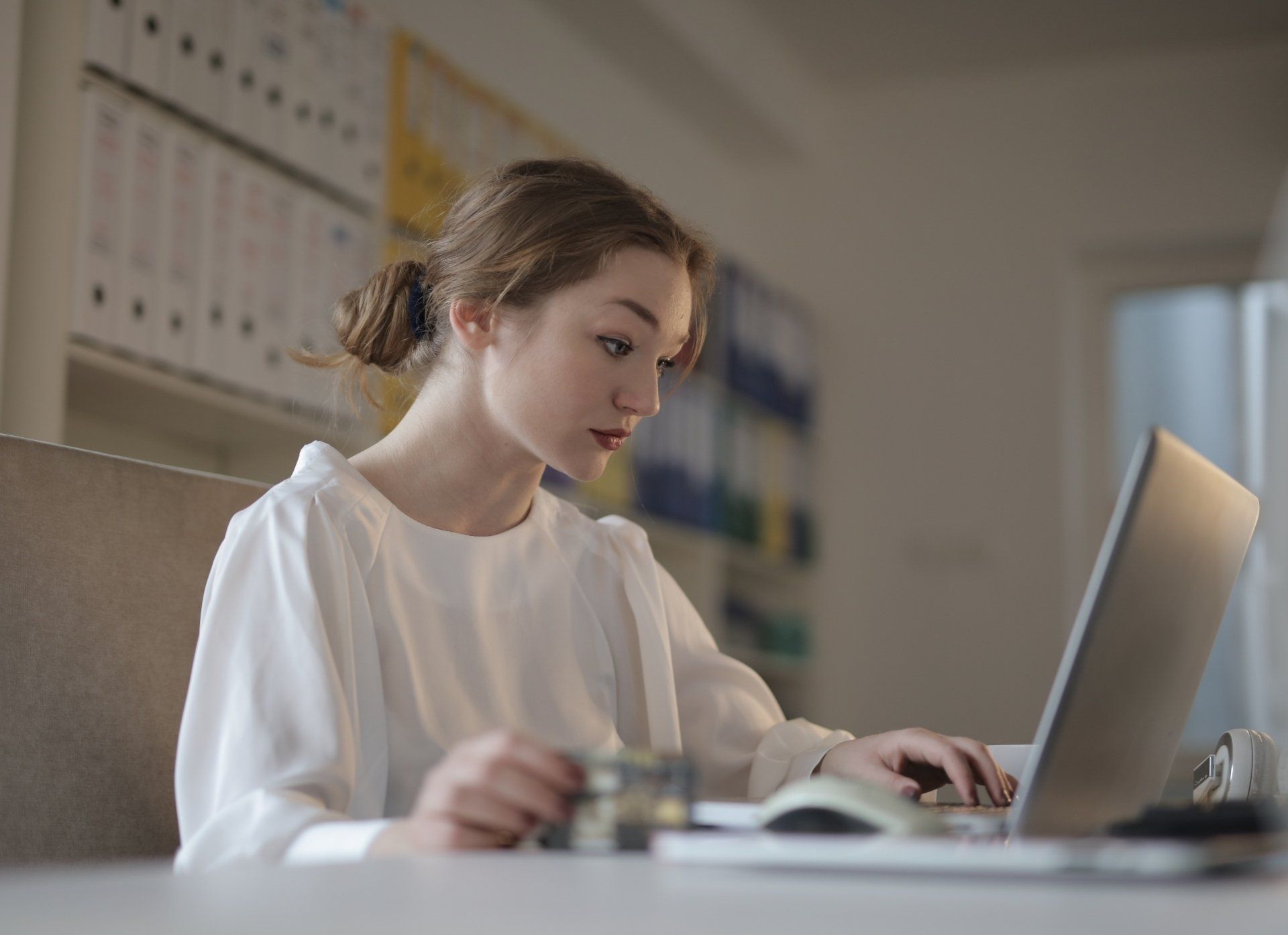 Uma mulher está sentada em uma mesa usando um laptop.