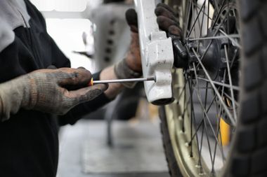 A person is working on a motorcycle with a screwdriver.