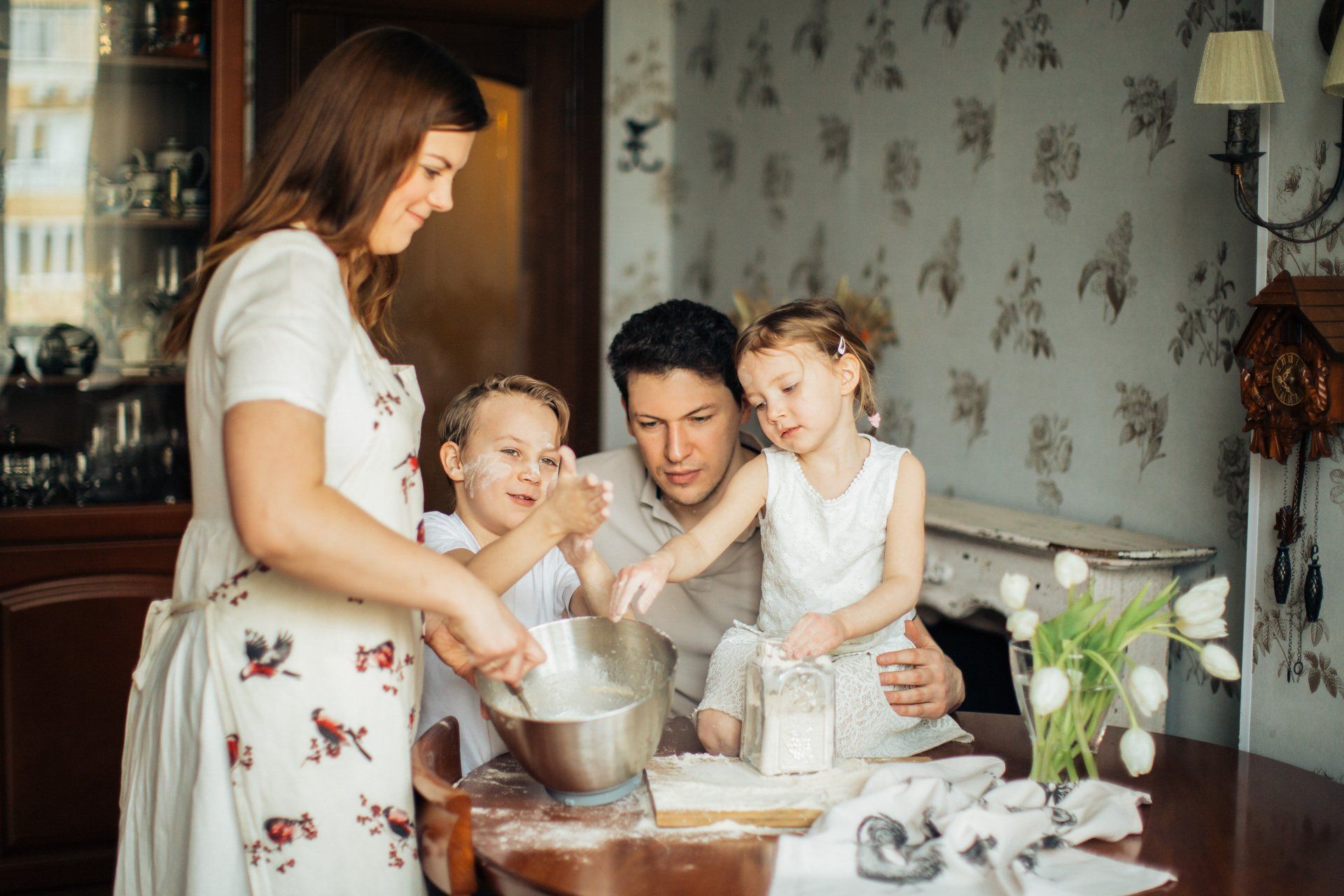 Family baking together in a cozy kitchen, mixing batter at a table by the window.