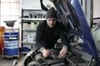 A man is working on the engine of a car in a garage.