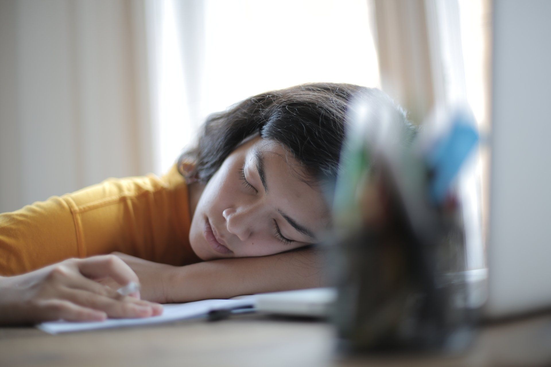 A woman is sleeping at a desk in front of a laptop computer.