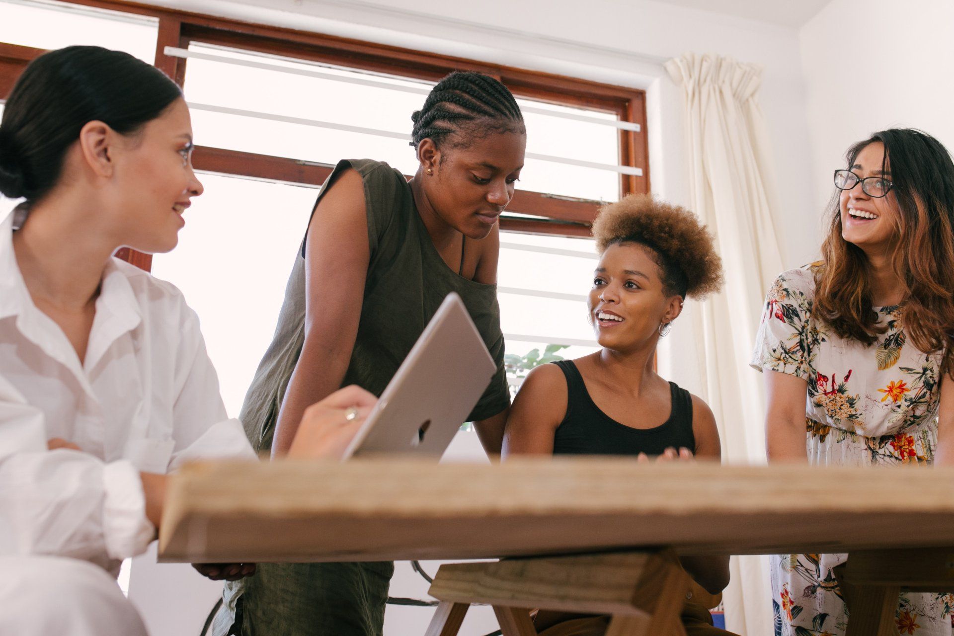 Photo of a woman standing by a conference table next to three people seated at the table.