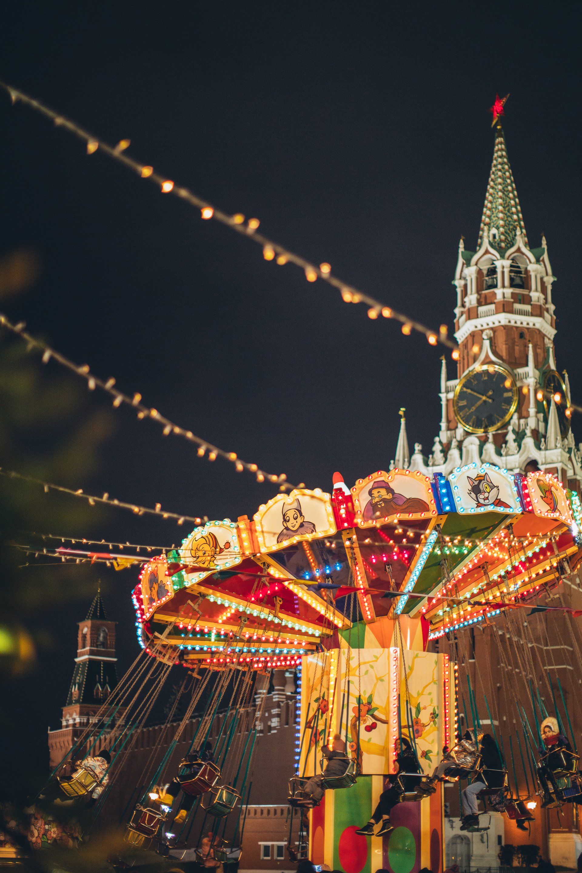 Carousel ride at night with illuminated spire in background.