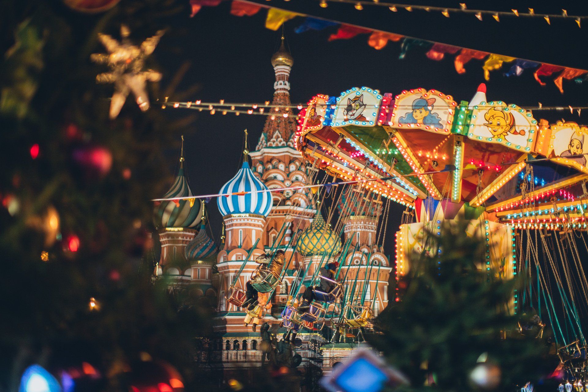 There is a carousel in the foreground and a christmas tree in the background.
