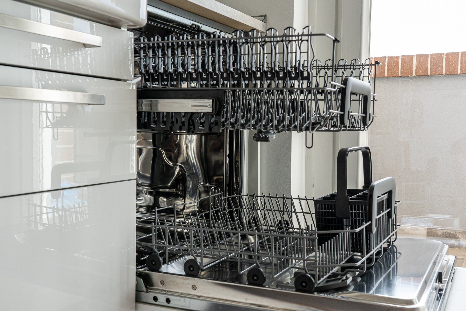 Dishwasher interior with black racks and open door, ready for loading.